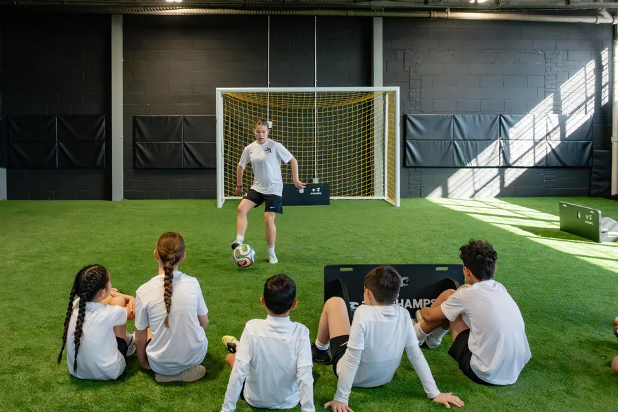 Coach demonstrating in front of the goal while players watch